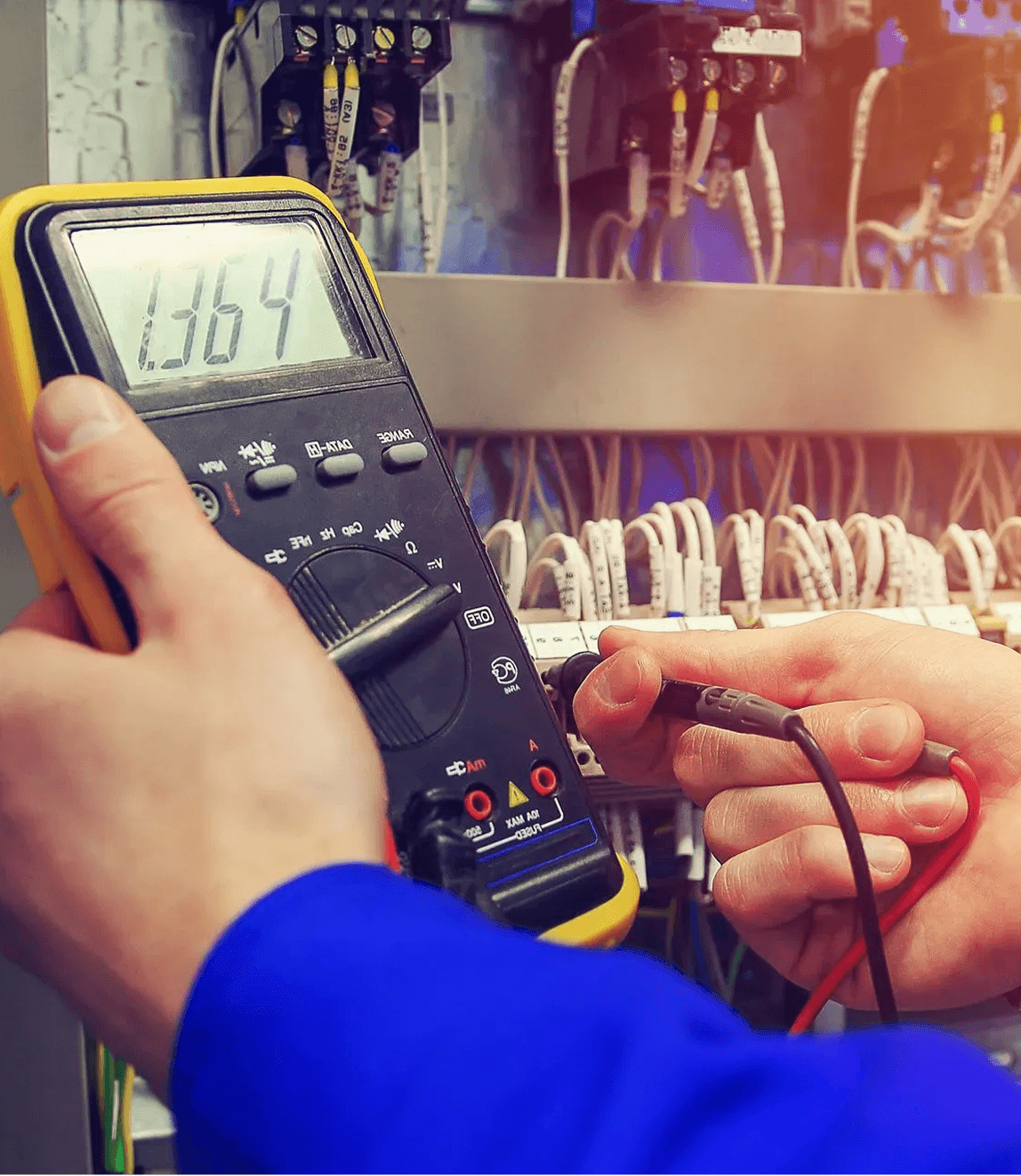 Electrician using multimeter for voltage measurement.