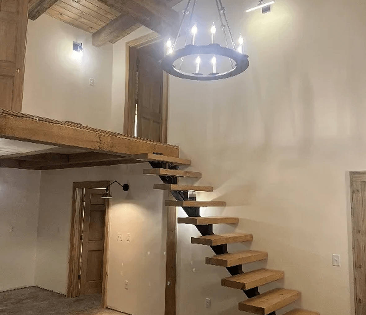 Wooden staircase and chandelier in rustic interior.