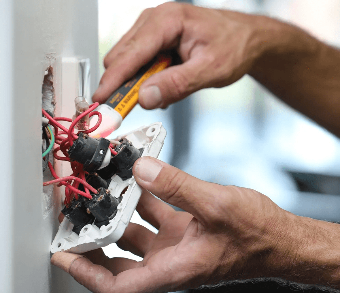 Electrician working on wall socket wiring.