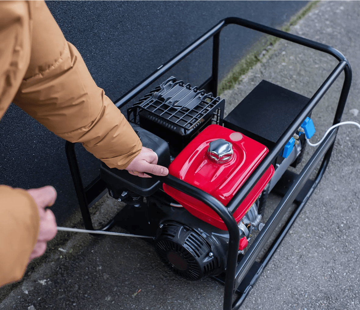 Person starting a portable generator outdoors.
