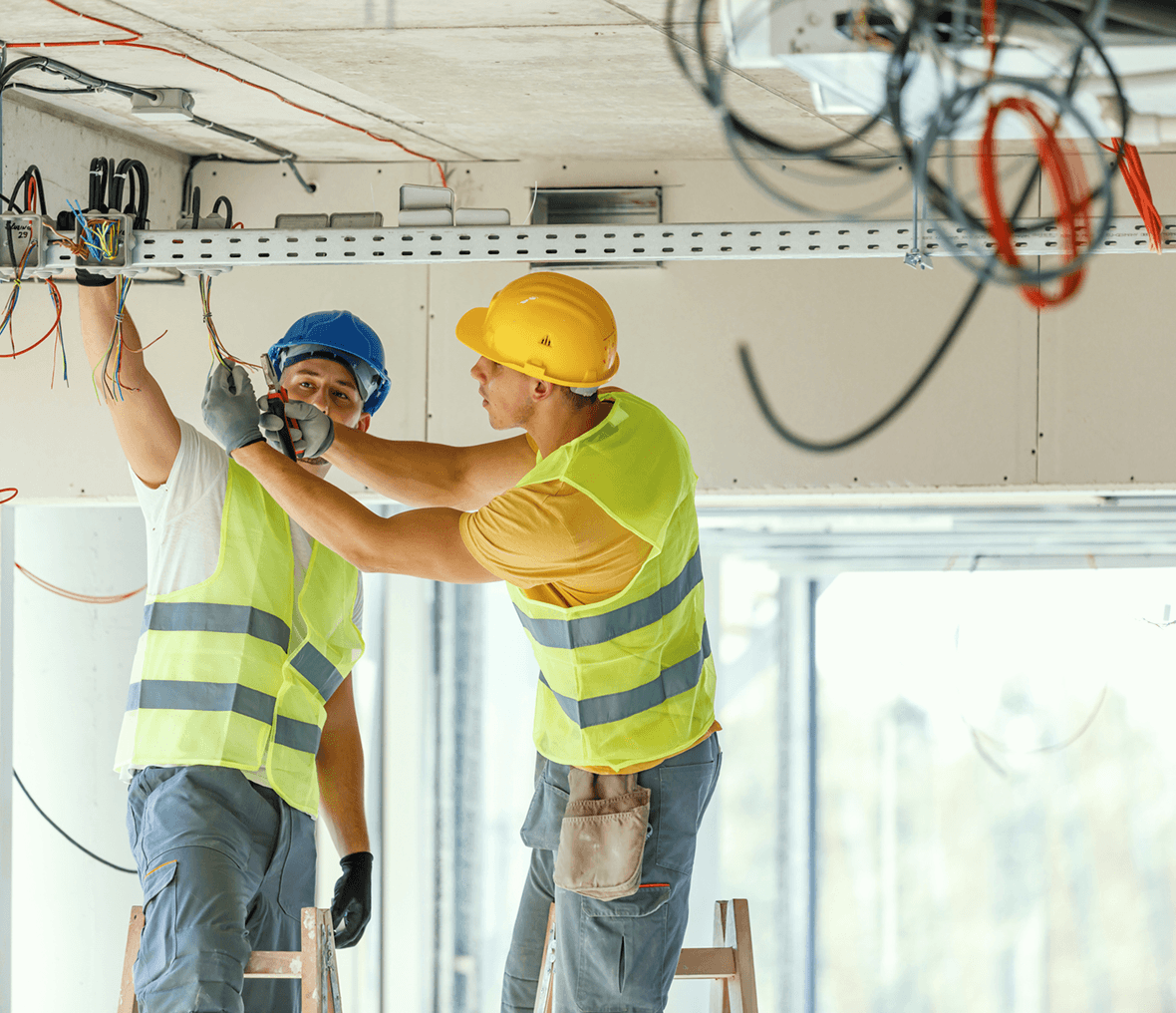 Electricians working on ceiling wiring installation.