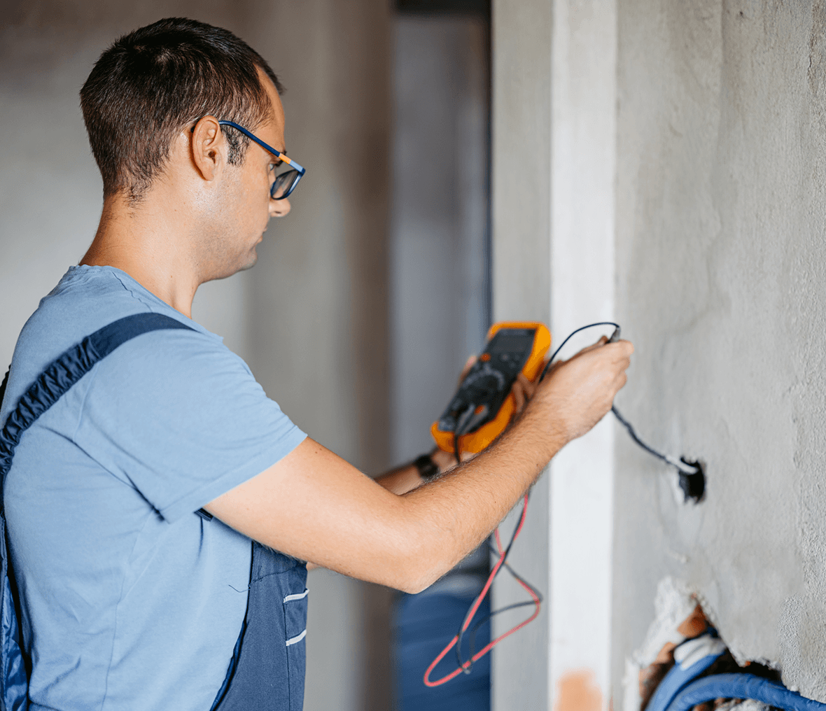 Electrician testing wires with a multimeter tool.