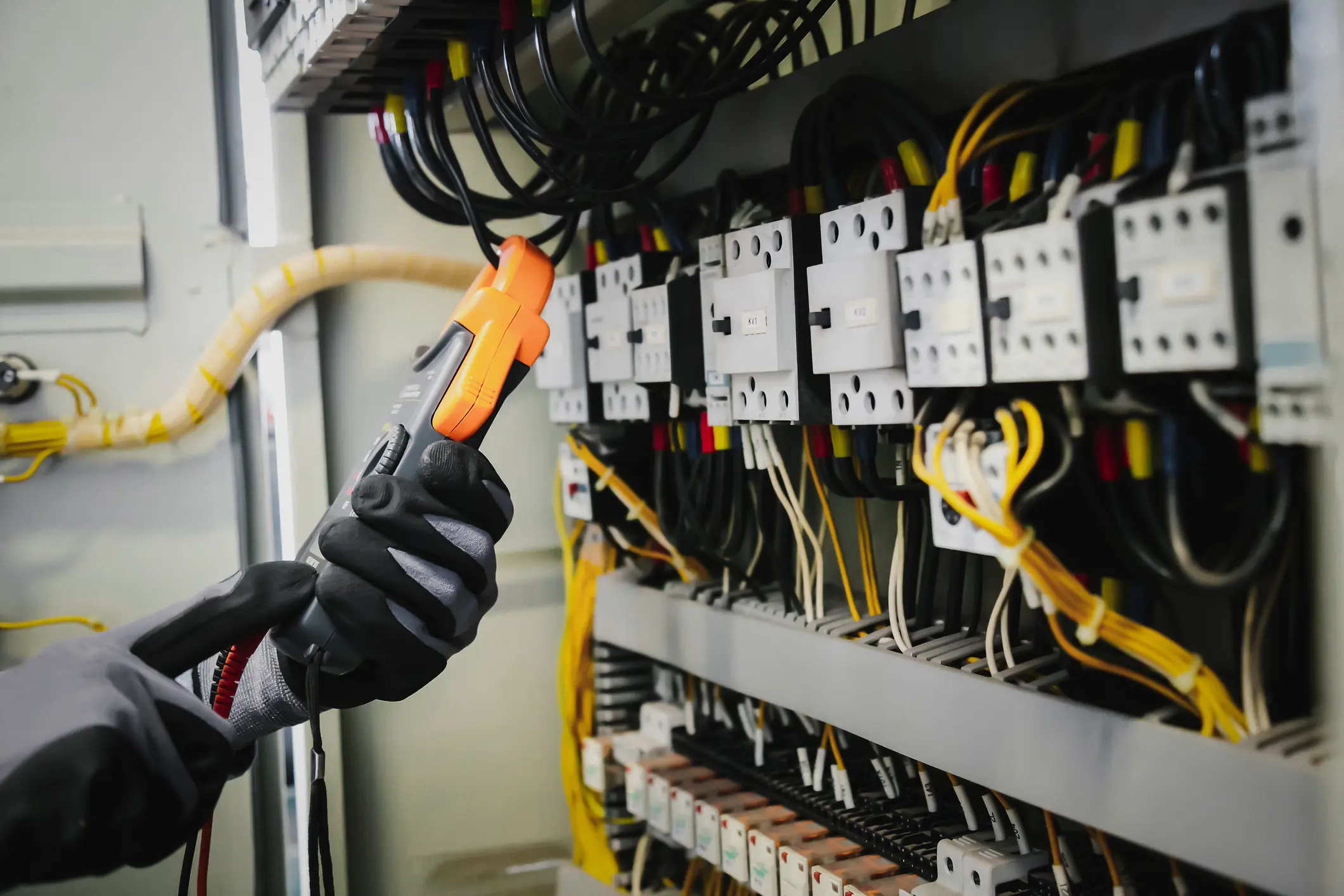 Electrical engineers test electrical installations and wiring on protective relays, measuring them with a multimeter.