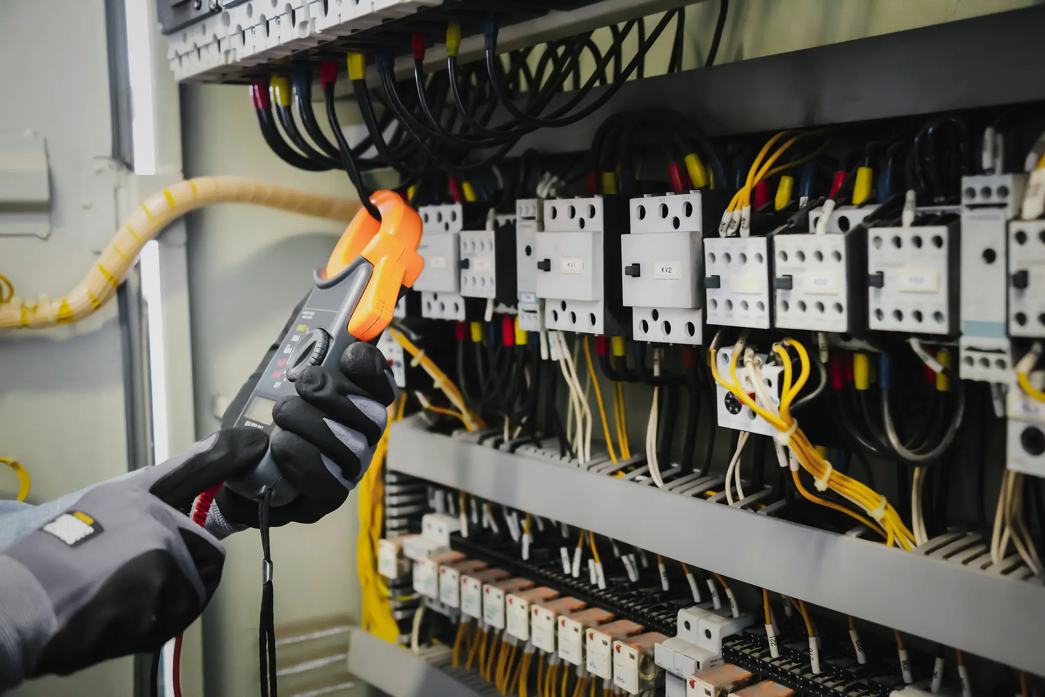 Electrical engineers test electrical installations and wiring on protective relays, measuring them with a multimeter.