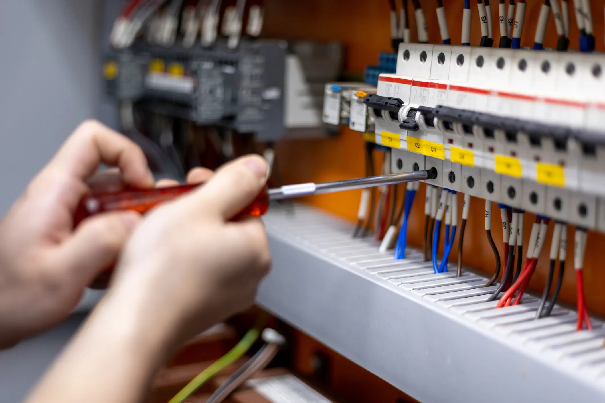 Engineer's hand is pressing a button to test a system in front of a control panel in an industrial factory.