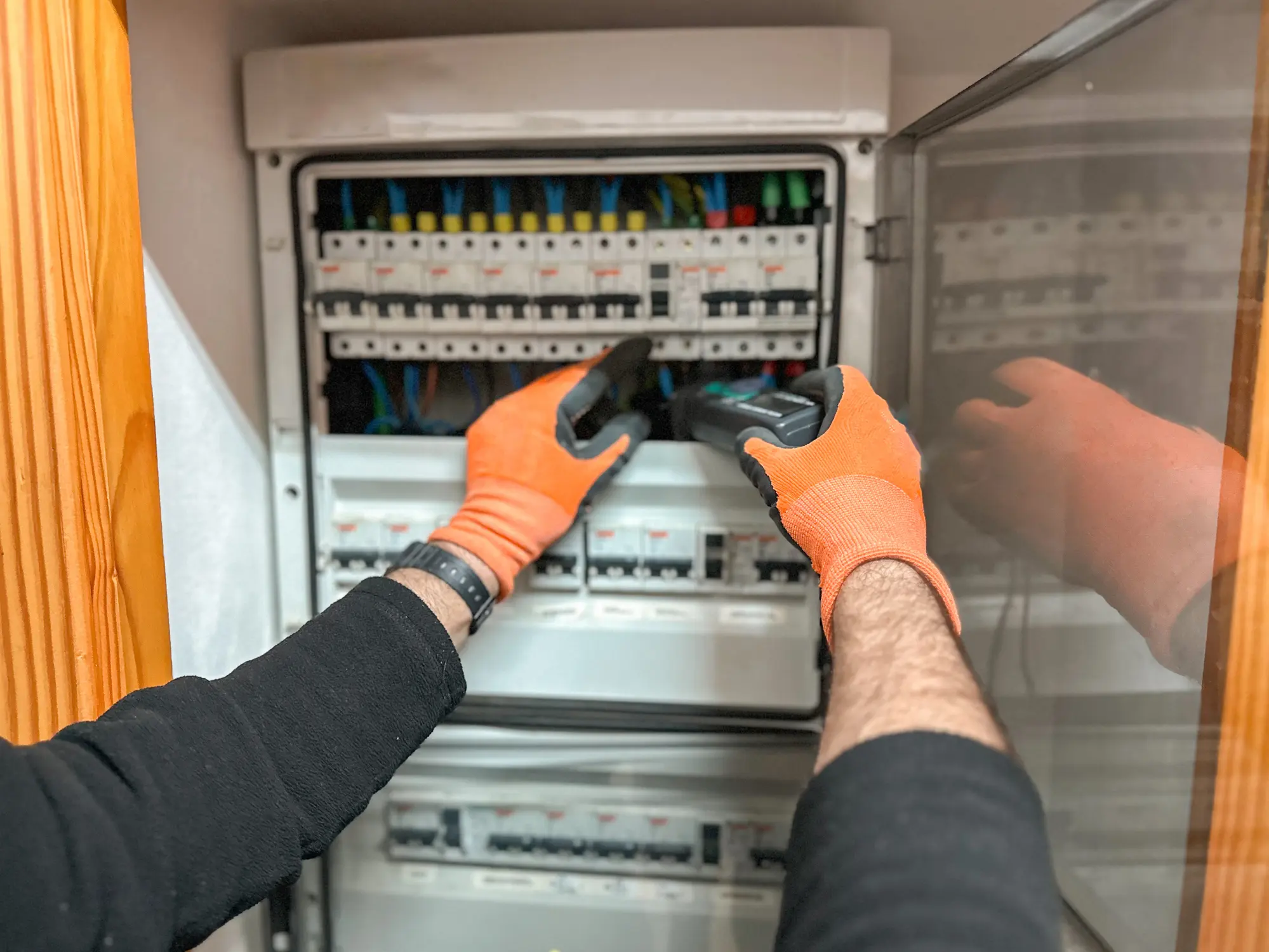 Electrician hands using digital clamp meter in a house electrical panel